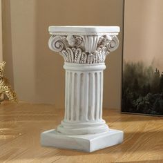 a white vase sitting on top of a wooden table next to a framed photo and a painting