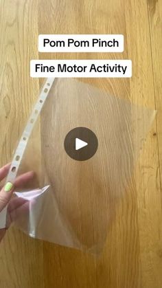 a person holding a piece of clear plastic on top of a wooden table with the text pom pom pinch fine motor activity