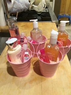 four pink buckets filled with soap and lotion on top of a wooden table