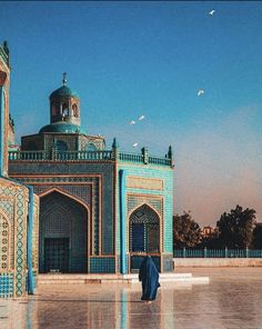 a person standing in front of a building with blue and green tiles on the walls