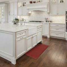 a large kitchen with white cabinets and wood floors