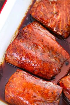 three pieces of cooked meat sitting in a pan covered in bbq gravy