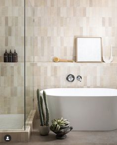 a white bath tub sitting next to a bathroom sink under a mirror on the wall