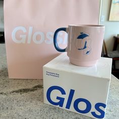 a pink coffee mug sitting on top of a box with the word gloss printed on it