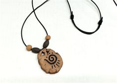 a necklace with a wooden bead and a stone pendant on a black leather cord