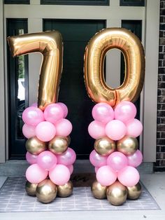 two large balloons that are shaped like the number seventy and one with pink and gold balloons