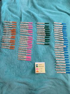 several different colored toothbrushes laying on a blue towel next to a small card