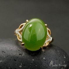 A statement piece that is bound to bring a vibrant and energetically enhanced essence to your days, this Statement Nephrite Jade Ring is both classic and contemporary. The center stone is a natural, untreated AAA nephrite jade stone of a statement-sized 11.75 carats, set in a four prong setting. With intricate details featuring 0.07 carats of sparking white diamonds on either side of the stone, this piece is set in a warm 18kt rose gold setting. Dimensions: Center Stone: Natural, untreated AAA N Elegant Green Ring With Large Stone, Elegant Green Rings With Large Stone, Elegant Large Stone Green Emerald Ring, Elegant Green Emerald Ring With Large Stone, Elegant Large Green Emerald Ring, 35th Wedding Anniversary, Jade Rings, Chinese Jade, Nephrite Jade