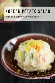 korean potato salad with fuji apples and cucumbers on a red plate in front of another dish