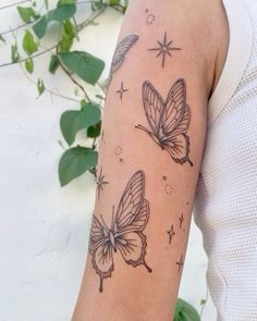 a woman's arm with two butterflies on it and stars in the sky above