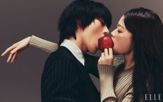 a man and woman kissing while holding an apple