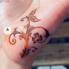 a hand with a tattoo on it that has an orange flower design on the wrist