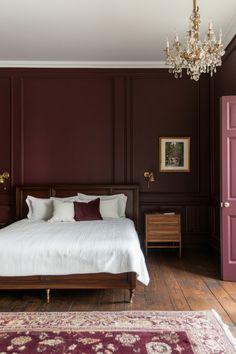 a bed sitting in a bedroom under a chandelier next to a wooden floor