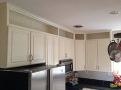 a kitchen with white cabinets and black counter tops, pots and pans hanging from the ceiling