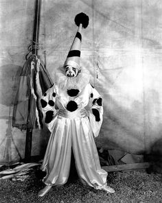 an old photo of a man dressed as a clown with his hands in the air