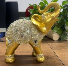 an elephant figurine sitting on top of a wooden table next to a plant