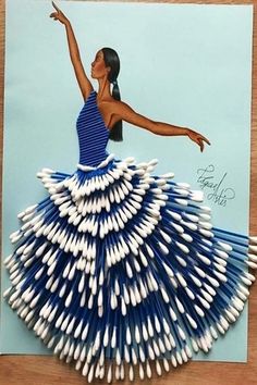 a card made out of toothpicks with a woman in blue and white dress