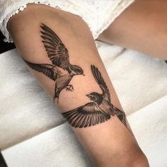 a woman's arm with two birds on it and one bird flying in the air