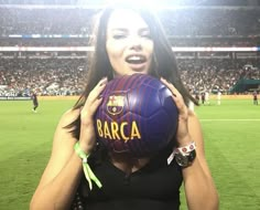 a woman is holding a soccer ball in front of her face at a sporting event