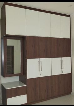 an empty room with white and brown cupboards, mirror and cabinet doors on the wall