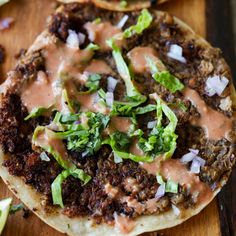 two tortillas on a wooden cutting board topped with meat and veggies