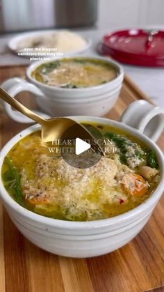 two white bowls filled with soup on top of a wooden cutting board