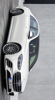 an aerial view of a white car parked next to a wall