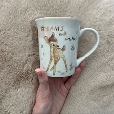 a hand holding a coffee cup with a deer on it