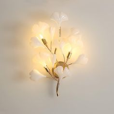 a light that is on the side of a wall with some flowers in front of it