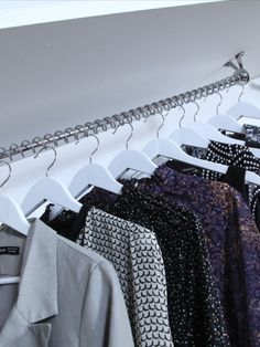 several shirts hanging on clothes racks in a closet