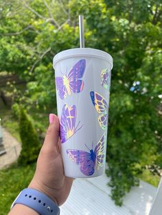 a person holding up a cup with butterflies on it