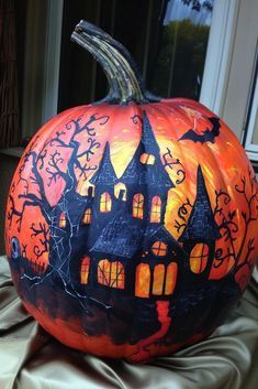 a pumpkin with a house painted on it