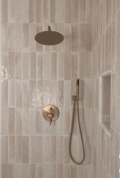 a shower head and hand shower in a tiled bathroom with beige tile on the walls