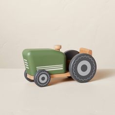 a green toy tractor sitting on top of a white table next to a brown wall