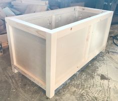 a wooden box sitting on top of a floor next to a pile of wood planks