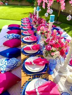 the table is set with pink and blue plates, napkins, and vases