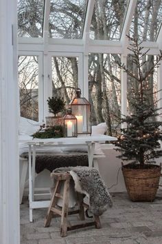 a white table with a lantern on top of it next to a small christmas tree