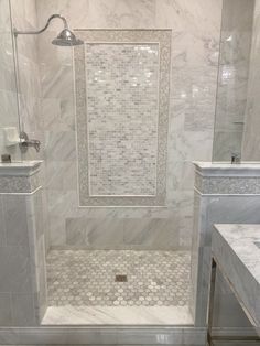 a white marble bathroom with two sinks and a walk in shower