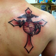 a cross tattoo on the back of a man's shoulder with a marine emblem