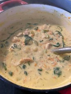 a large pot filled with soup on top of a stove next to a wooden spoon