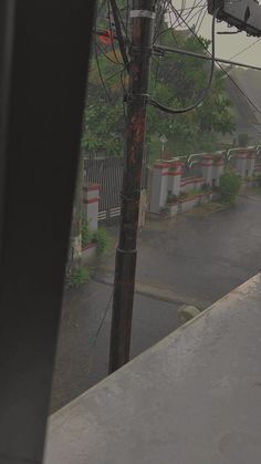 an overhead view of a street with power lines in the foreground and trees on the other side