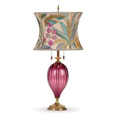 a table lamp with a pink glass base and floral print shade on the top,