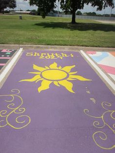 a purple and yellow painted parking lot with trees in the background