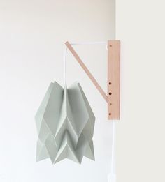 an origami lamp hanging on the wall next to a light fixture with a wooden frame