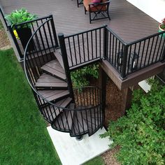 a spiral staircase in the middle of a deck with chairs and potted plants on it