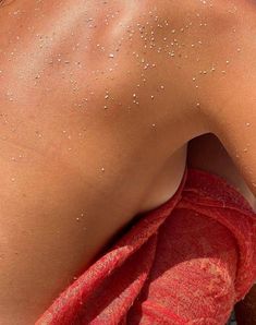 the back of a woman with white spots on her body and red towel around her neck