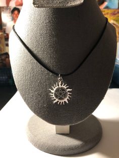 a necklace with a sun on it sitting on a mannequin