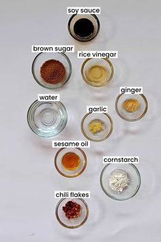 the ingredients to make this recipe are shown in bowls on a white table top, including sugar, brown sugar, rice vinegar, garlic oil, and chili flakes