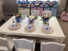 a white table topped with plates and vases filled with flowers on top of it