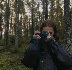 a woman taking a photo in the woods with her camera